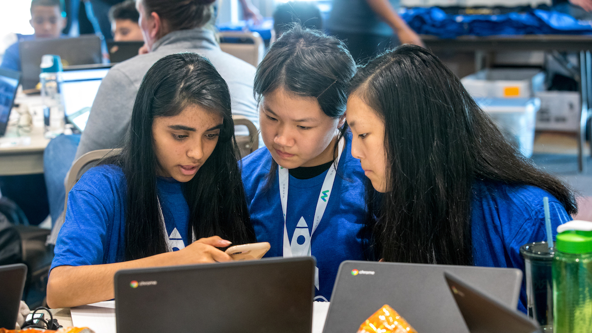 three female students looking at a smart phone