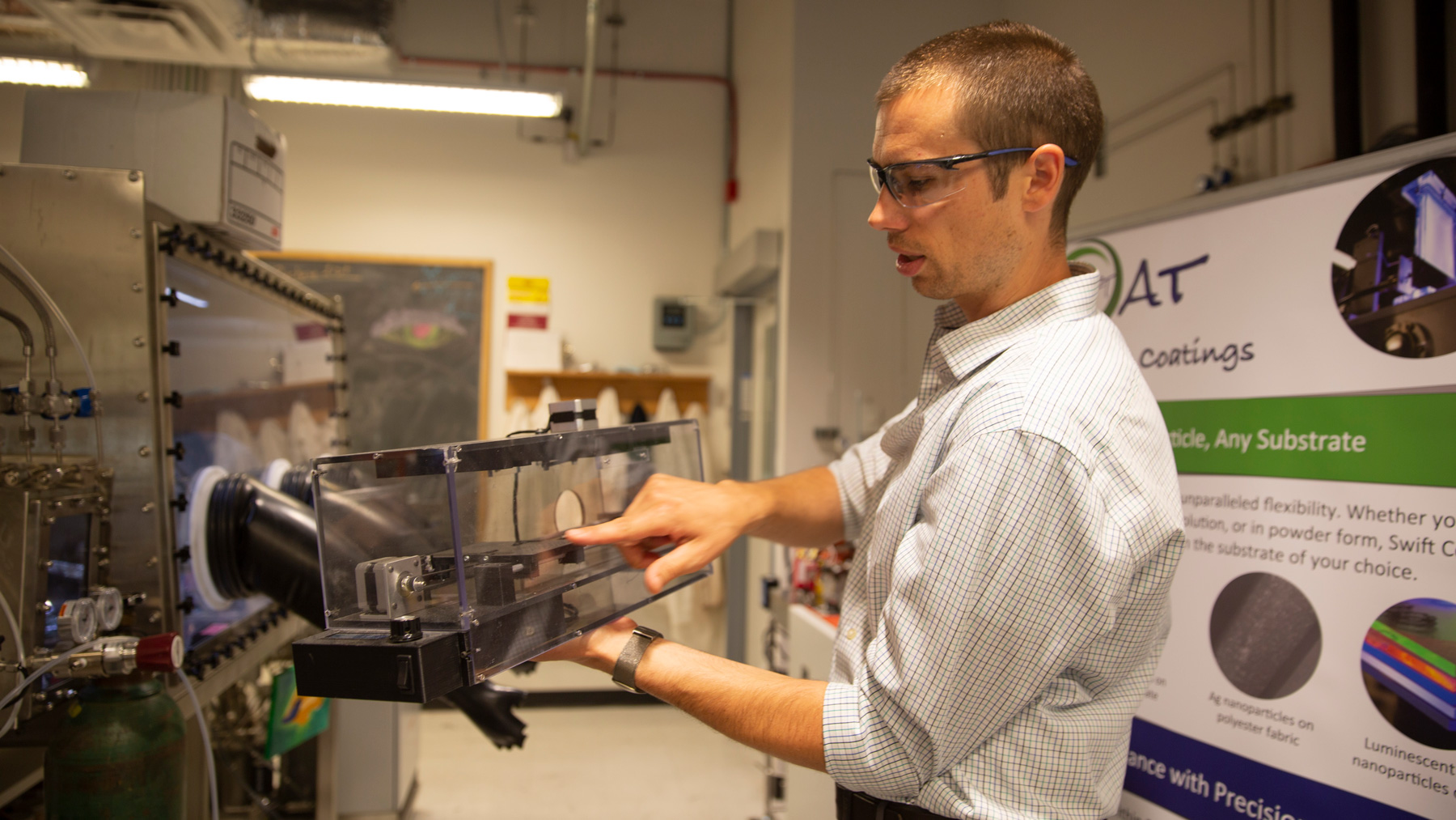 Zachary Holman holds a model of the deposition tool.