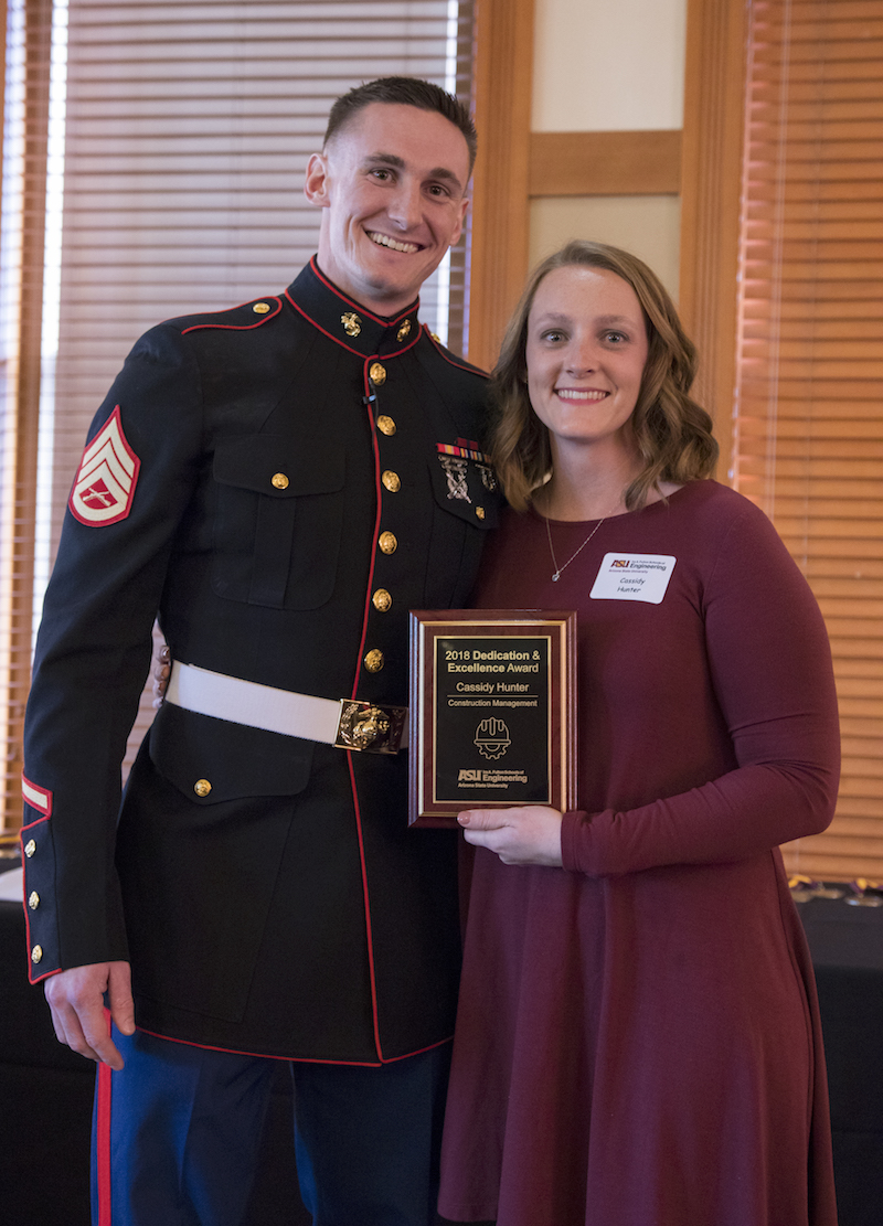 siblings standing next to each other holding a plaque