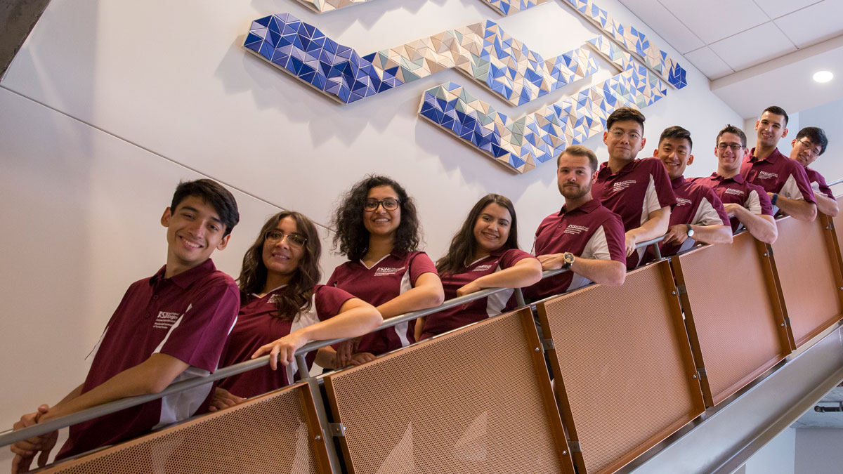 Students in maroon shirts lined up on a staircase.