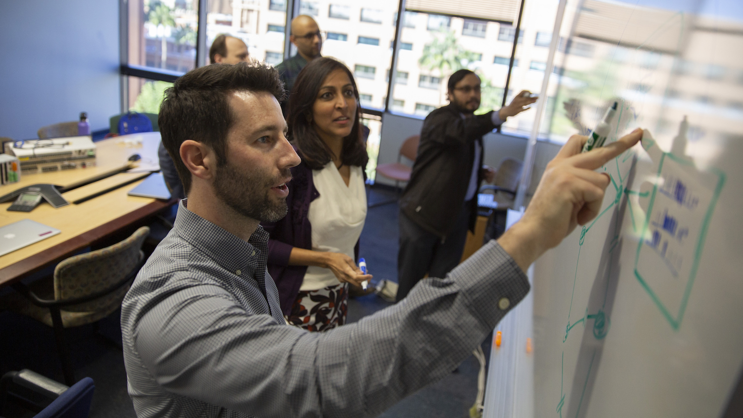 student writing on a white board with professor next to him