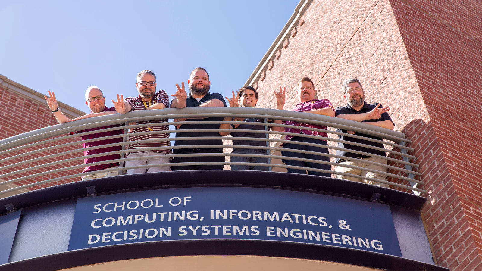 School of Computing, Informatics, and Decision Systems Engineering information technology team poses on a balcony.