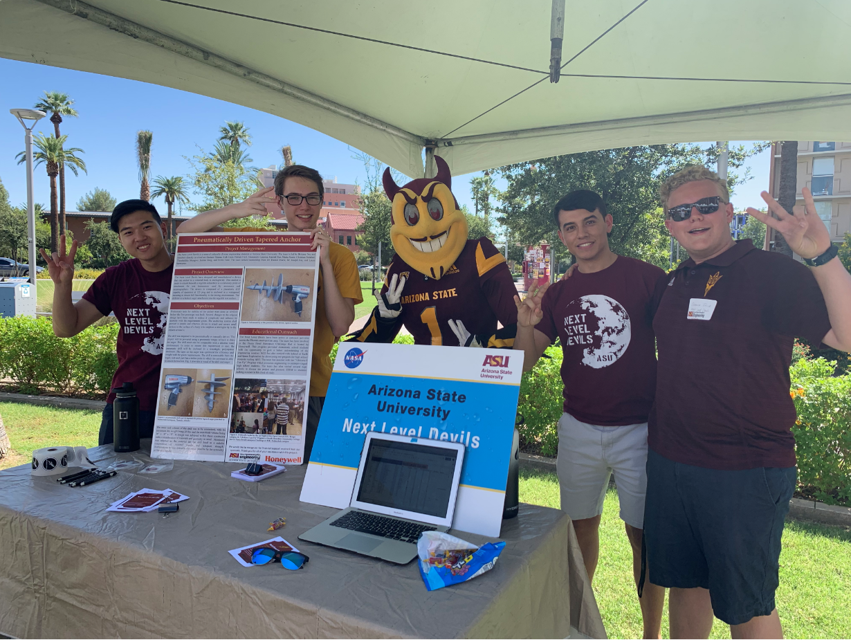 Four students from the Next Level Devils student team pose at an event with Sparky the Sun Devil