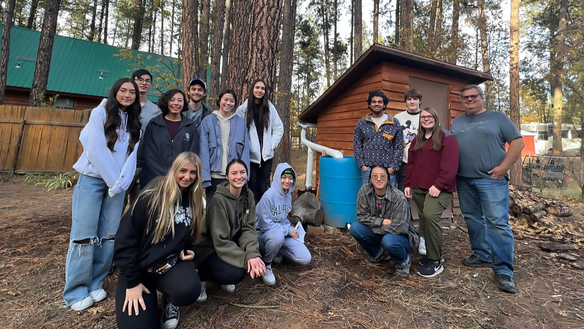 Students from Engineers Without Borders pose for a photo in the woods, where they conducted a prototyping session of a device they built