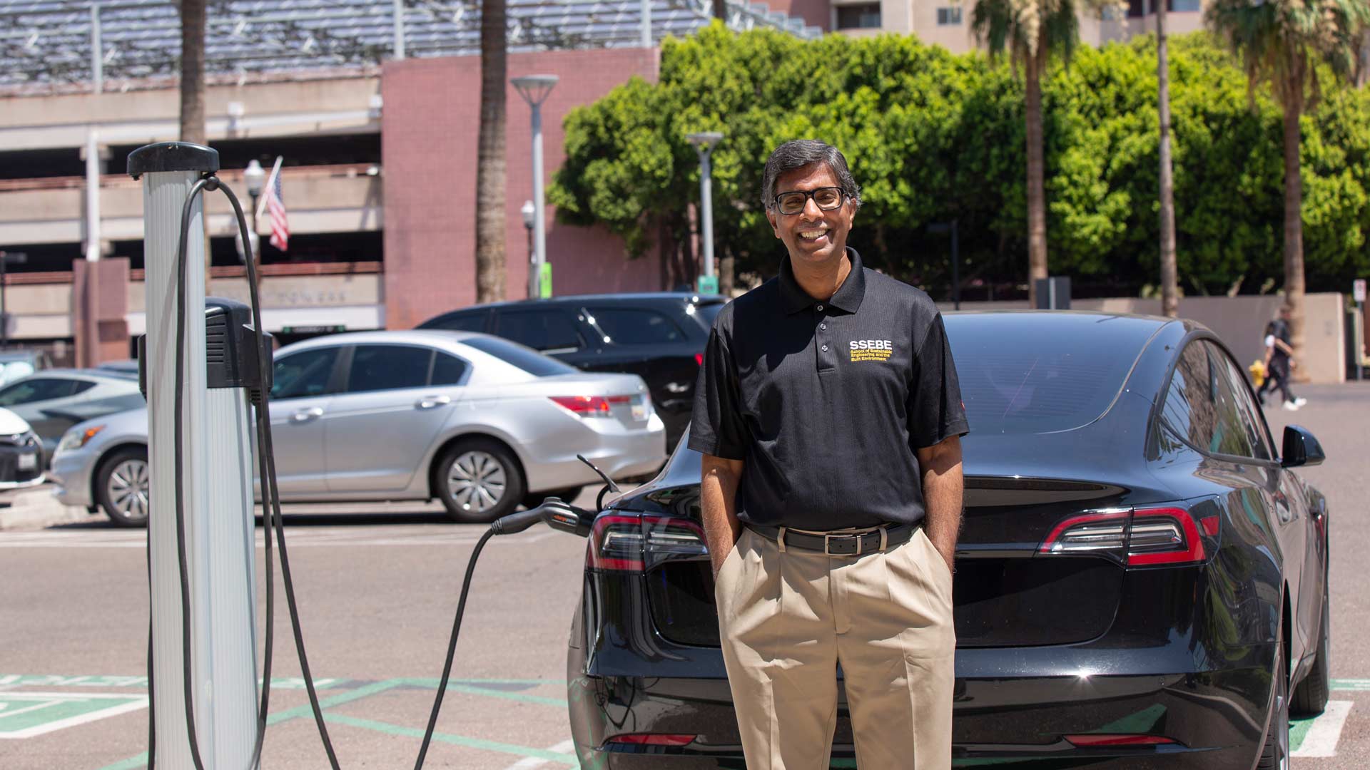 Ram Pendyala standing next to an electric vehicle charging station