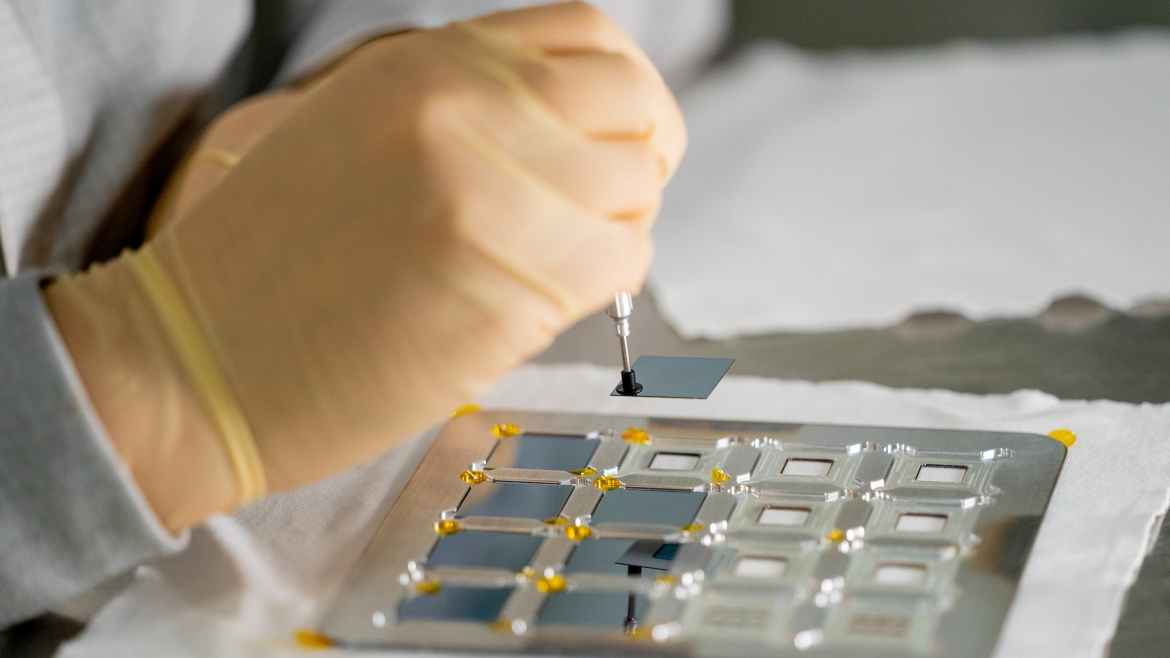 A close-up photo of gloved hands working with semiconductor chips.