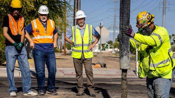 Four people in hard hats and high-visibility vests work on a construction site.