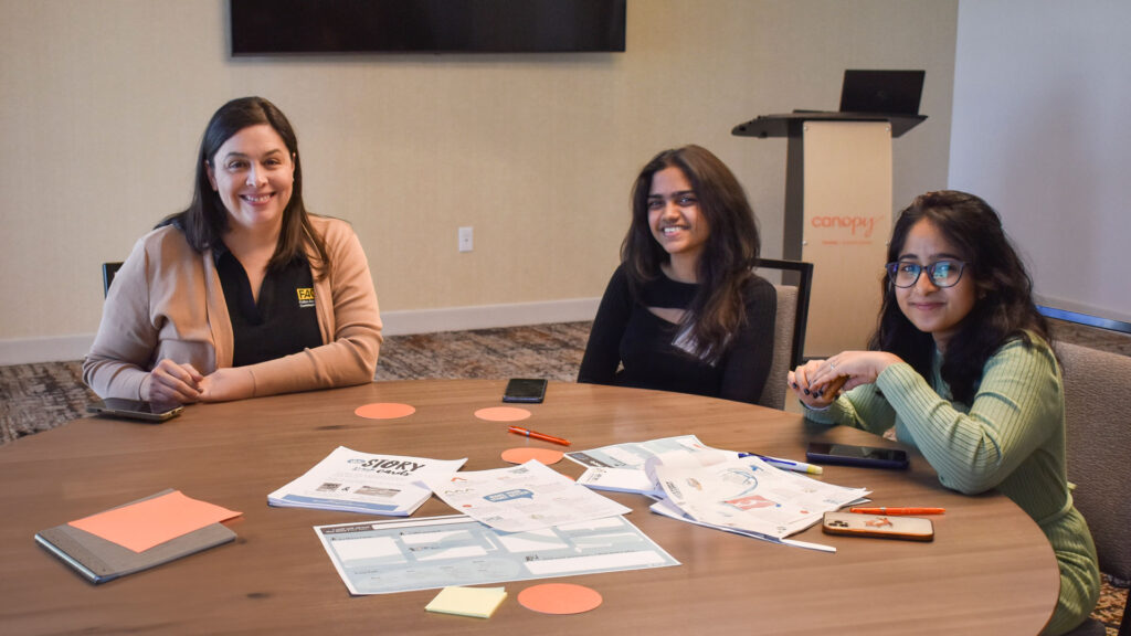 Tami Coronella works at a table with two students during the 2023 Women in Fulton Retreat.